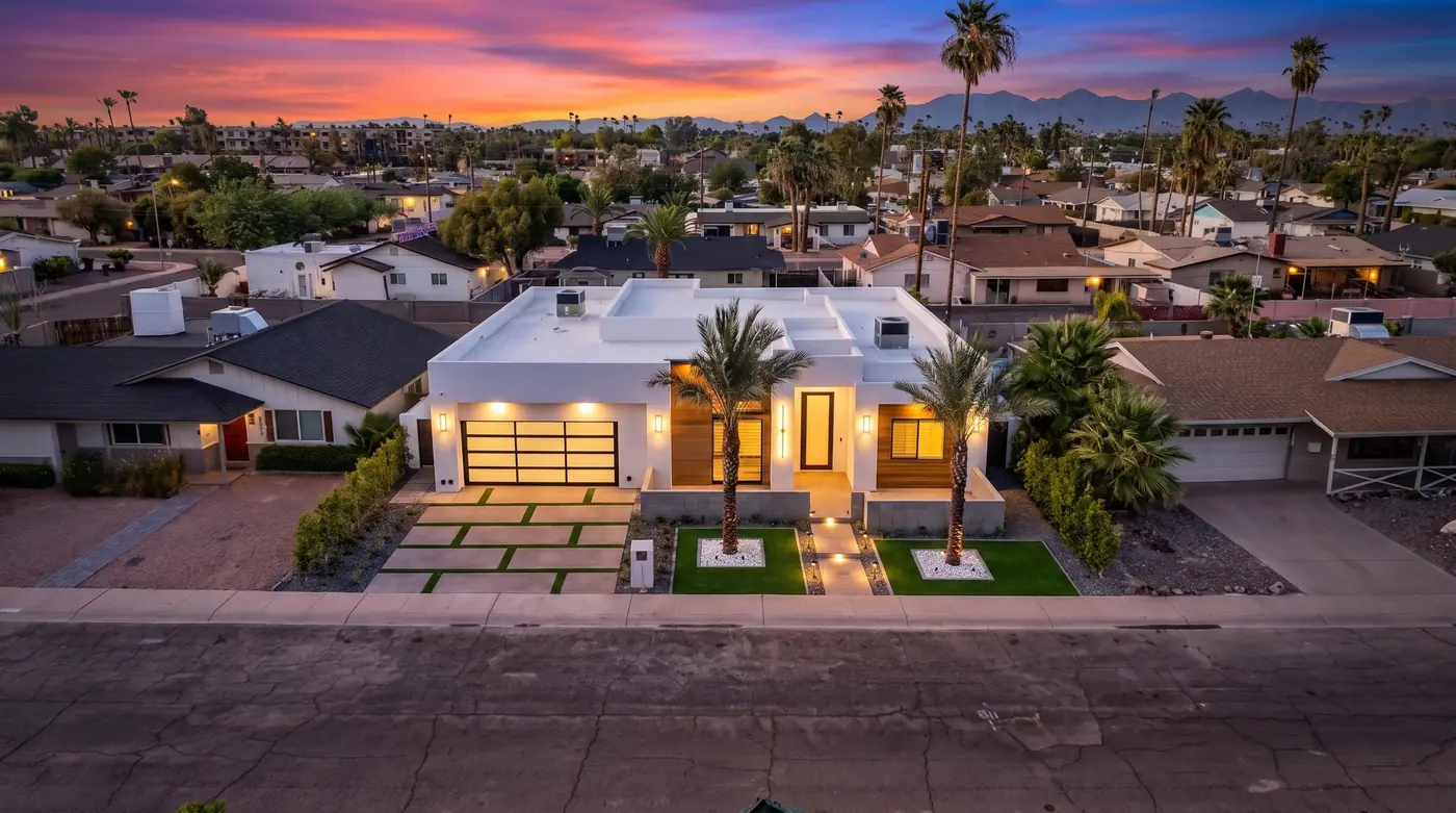 Drone view of a lit home at dusk with mountains behind